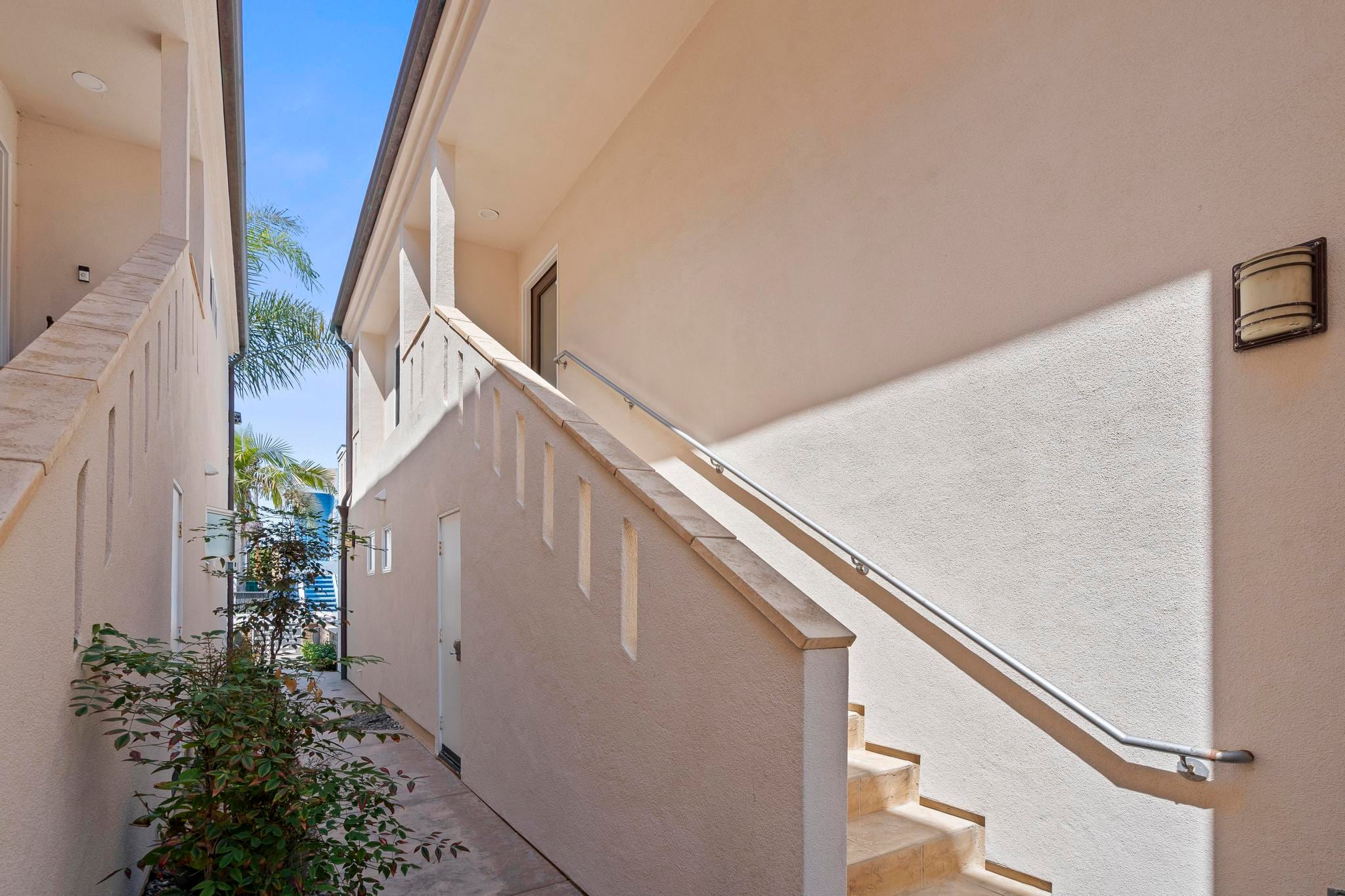 The exterior stair up to Belmont Beach House, with a palm and blue sky above