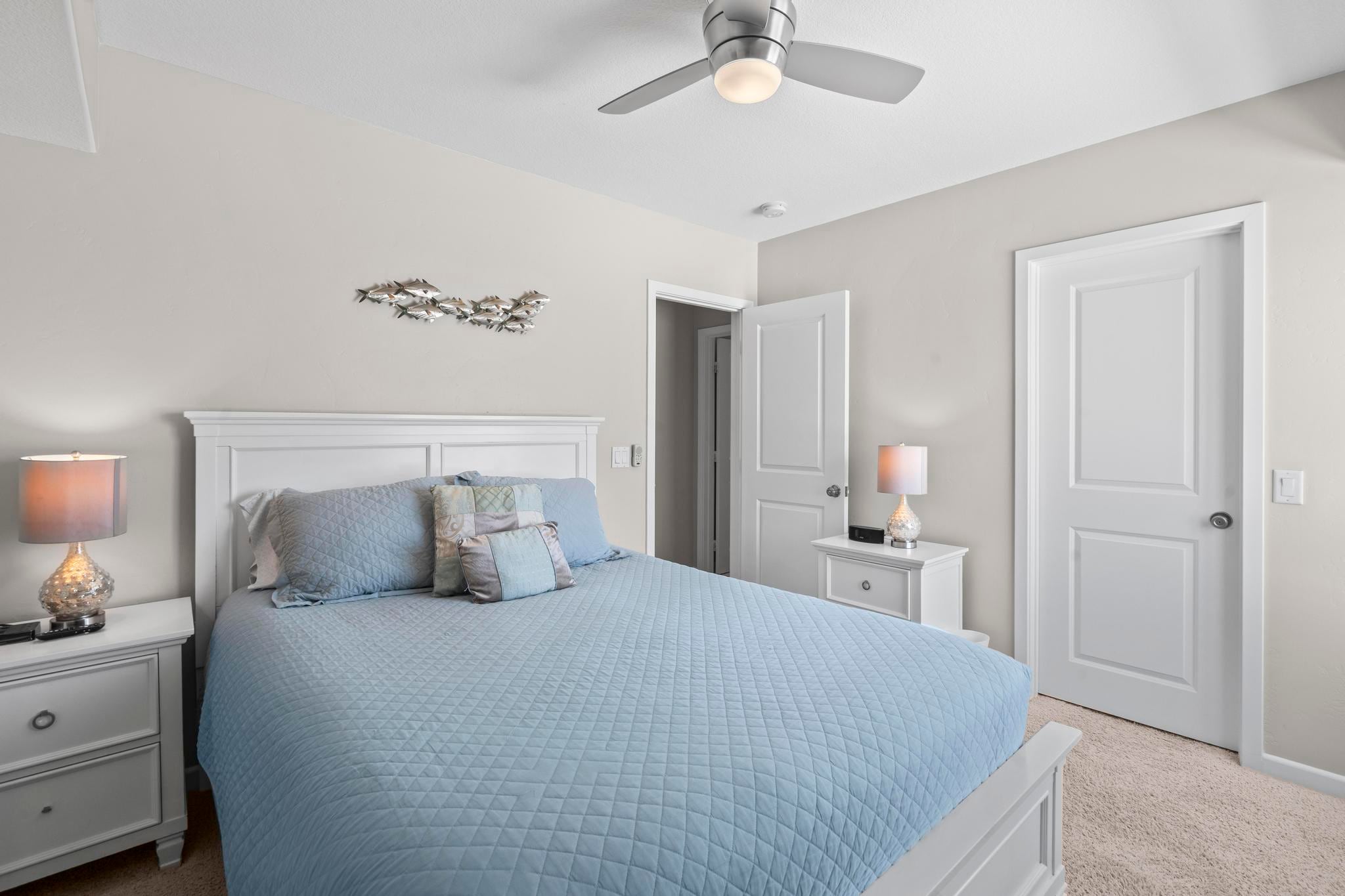 A bedroom at Belmont Beach House with a white bed, blue linens and a ceiling fan