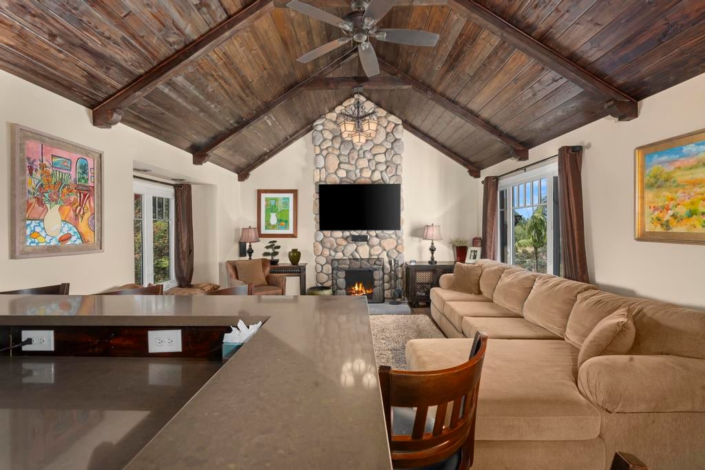 The living room at Kensington Canyon with a vaulted wood ceiling, a river-rock fireplace and a long sofa
