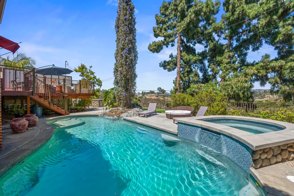 The pool and spa at Kensington Canyon, edged in river rock beneath tall trees