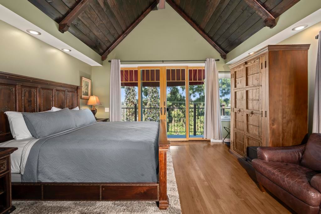 A bedroom at Kensington Canyon with a wood ceiling, a wood bed and French doors to a balcony