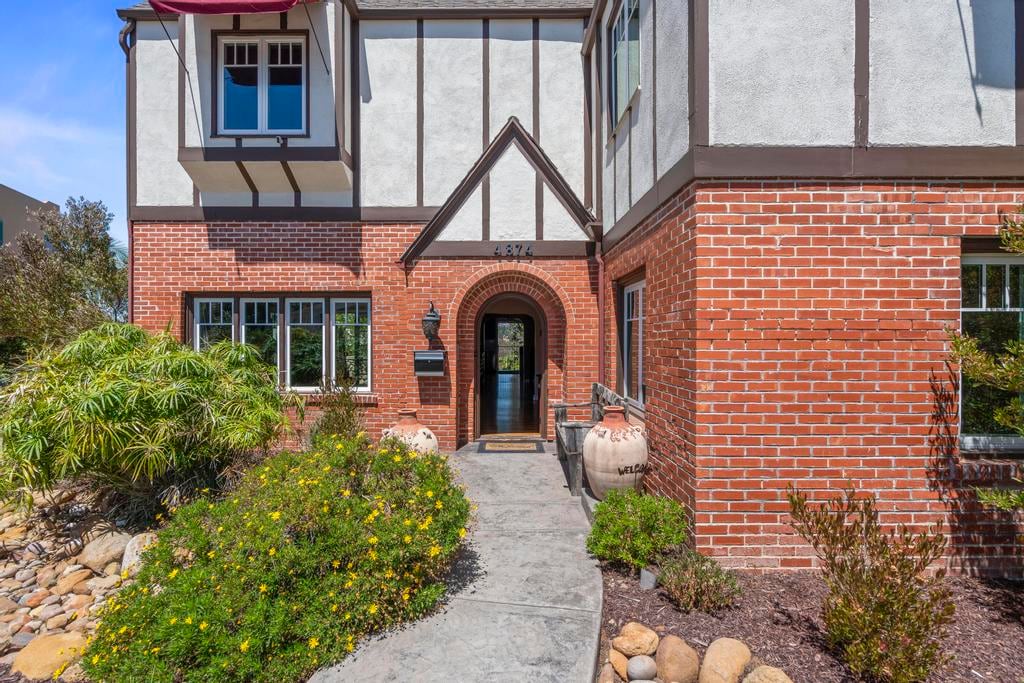 The arched front door of Kensington Canyon set in brick, with a stone path and planting