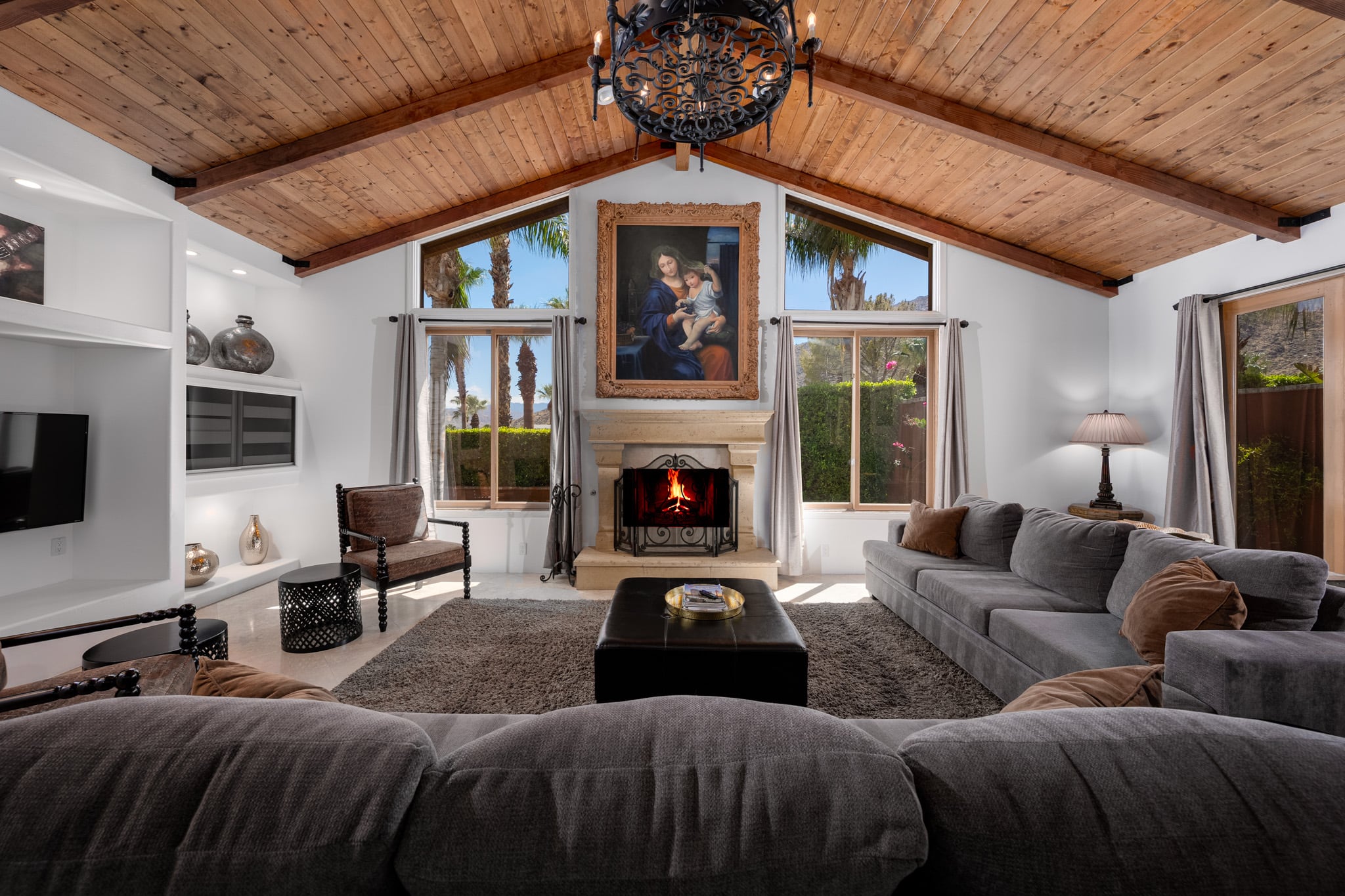 The great room at Mercury Palms with its wood cathedral ceiling, stone fireplace and deep grey sectional