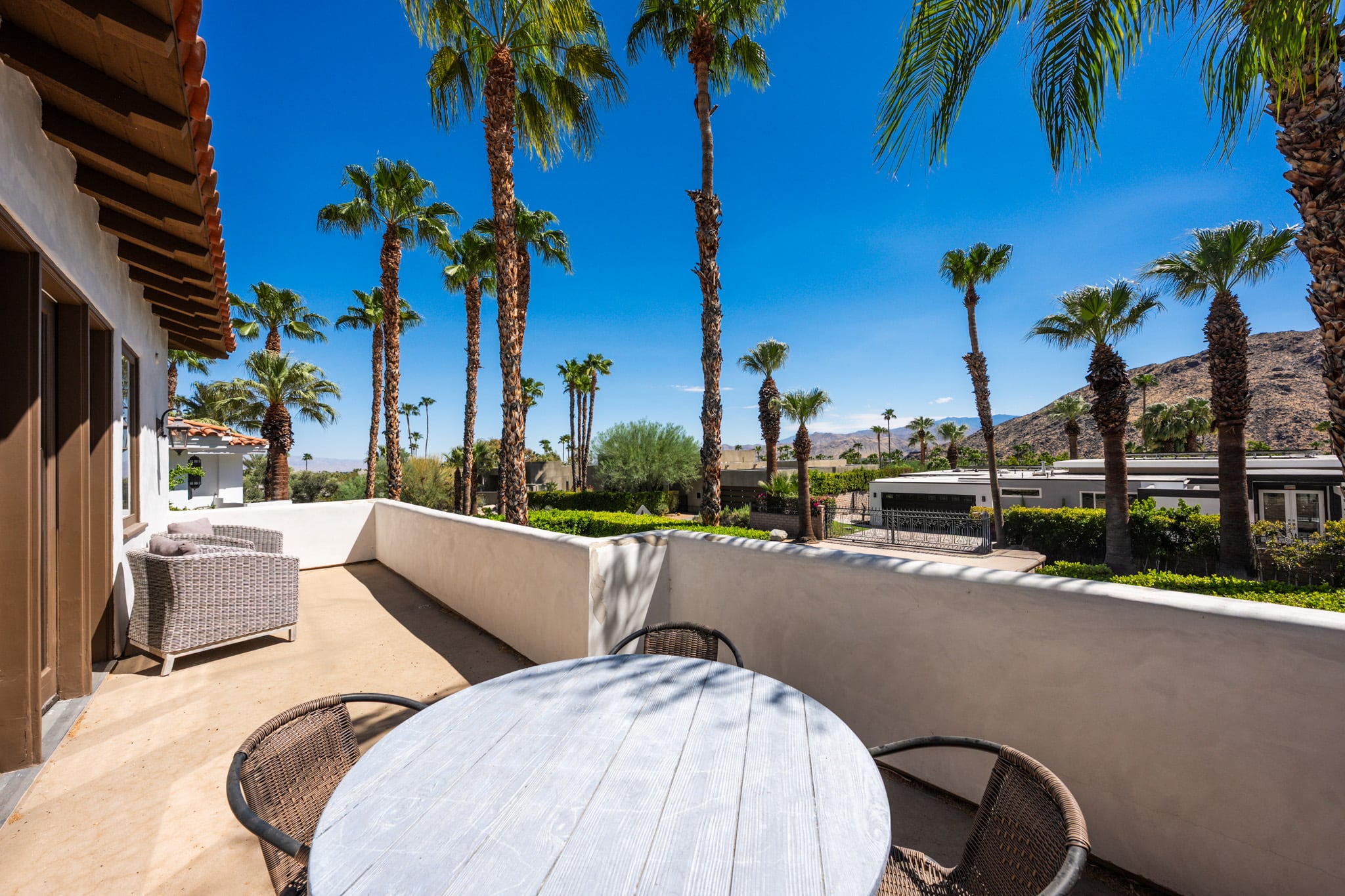 An outdoor dining terrace at Mercury Palms under tall palms with the mountains beyond