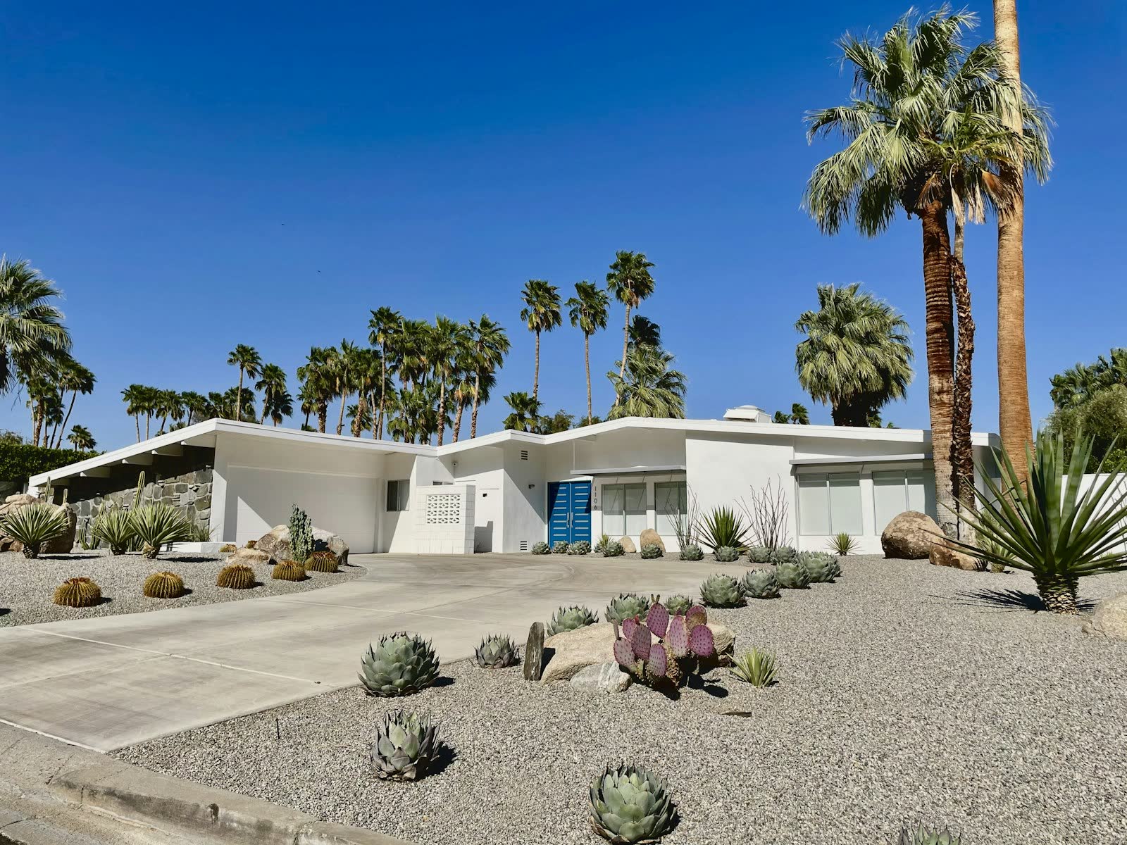 White mid-century modern home with palm trees and desert landscaping in Palm Springs, California