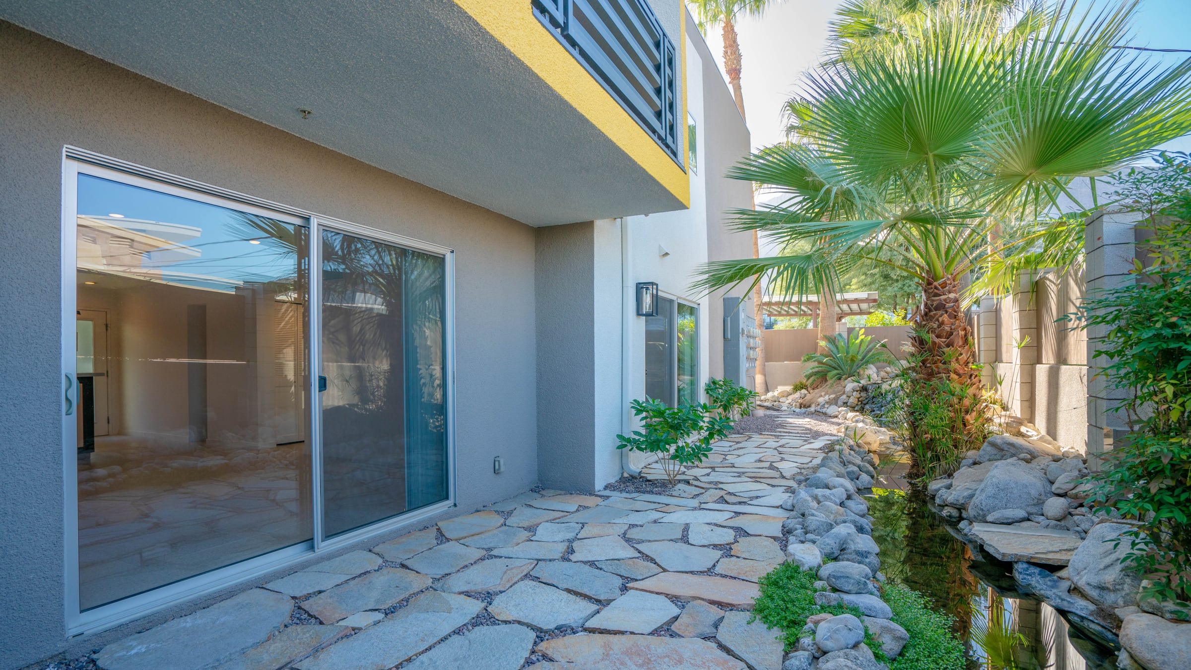 Back patio of Unit 104 before, open to the walkway with little planting