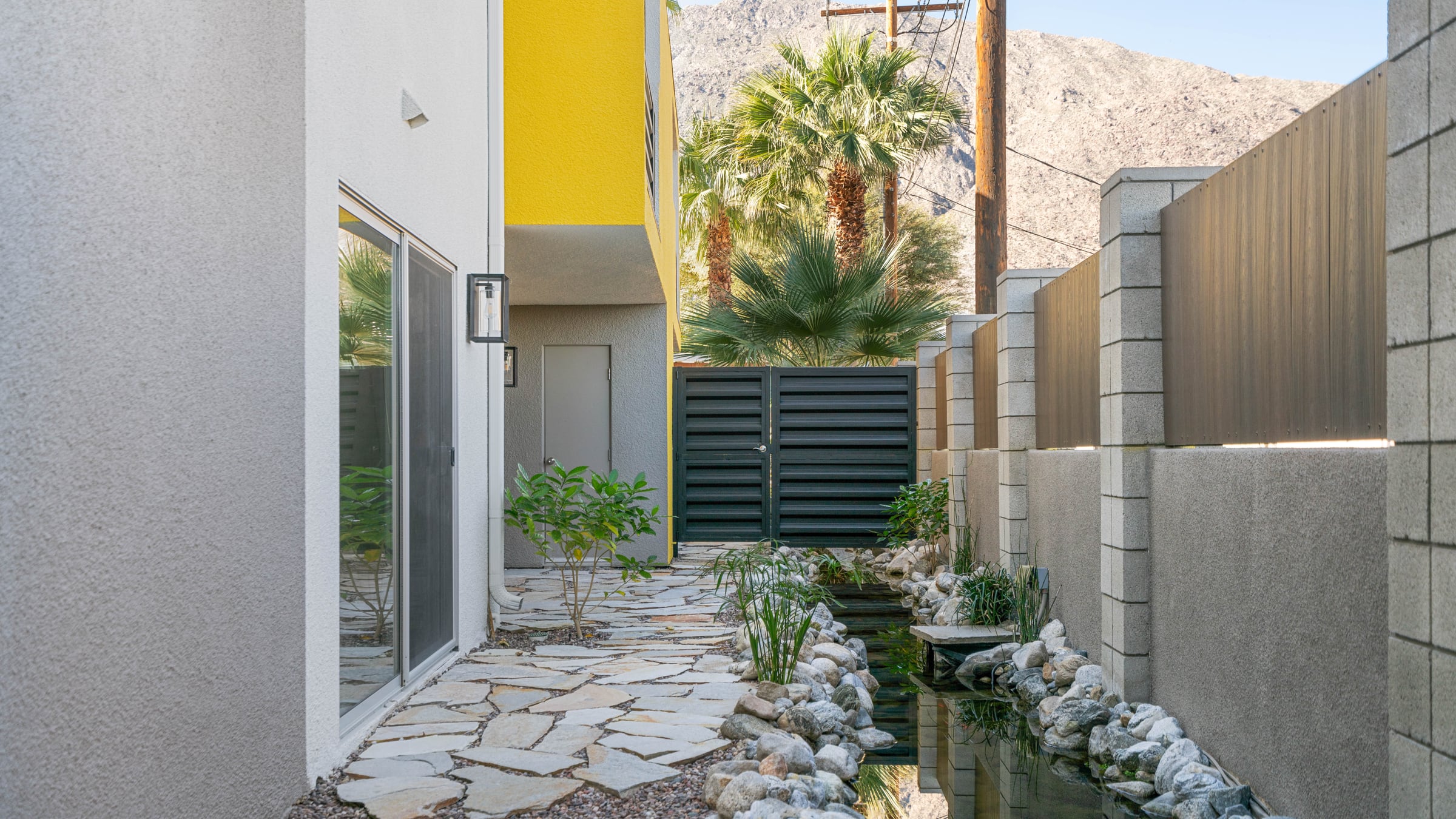 Koi pond beside Unit 105 before planting: rock, water and bare banks