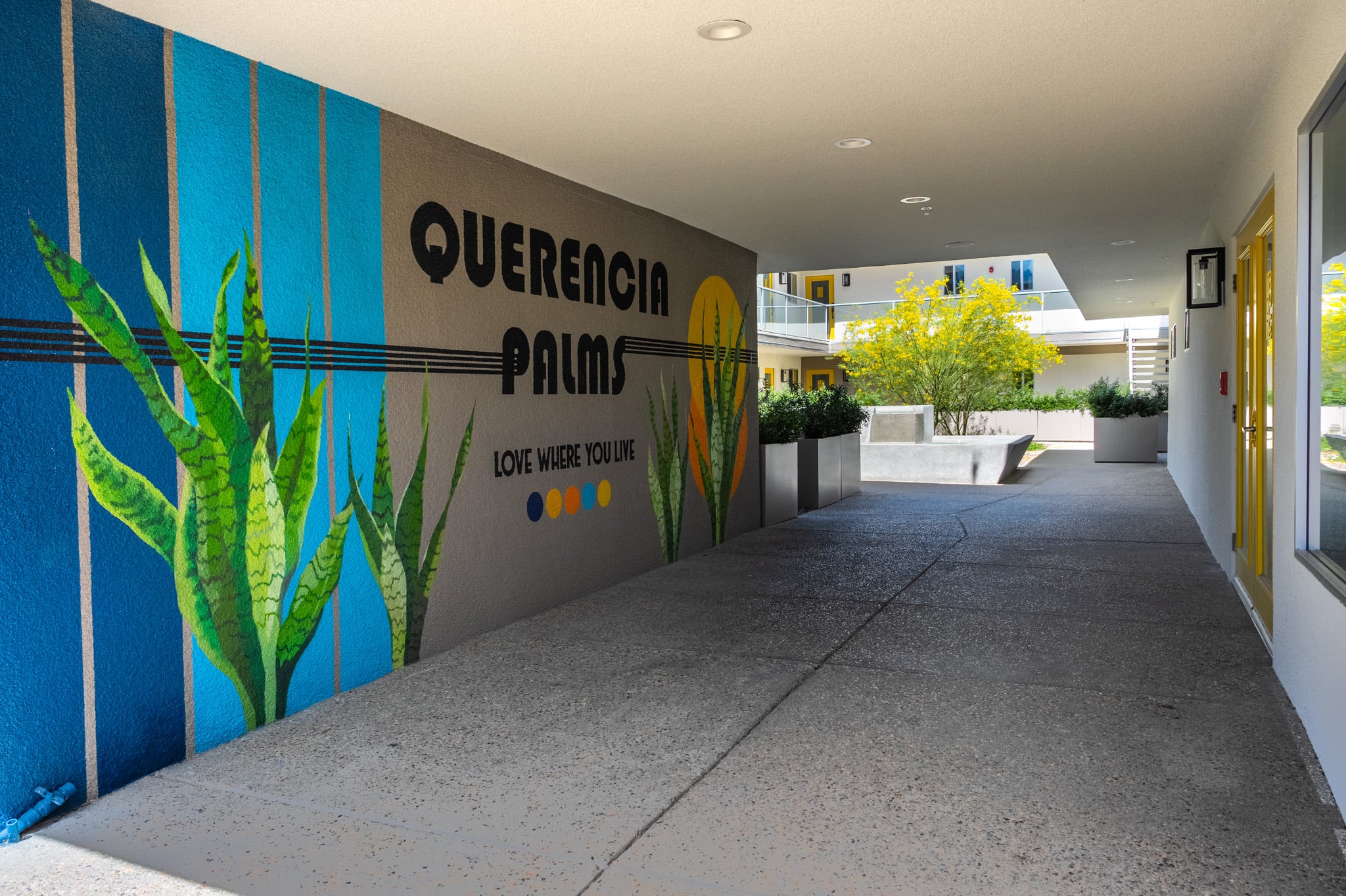 The covered breezeway at Querencia Palms with the painted mural reading Querencia Palms, love where you live